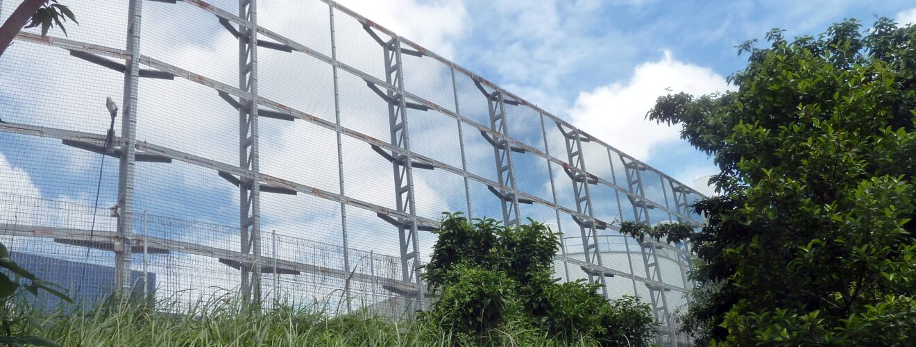 A massively high fence. What is it protecting? Singapore's Kaiju Farm?